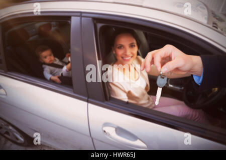 Le client reçoit des clés de voiture contre mère avec son bébé dans le siège de voiture Banque D'Images