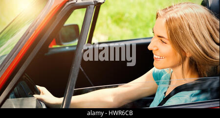 Smiling Beautiful woman driving red cabriolet pendant journée ensoleillée Banque D'Images