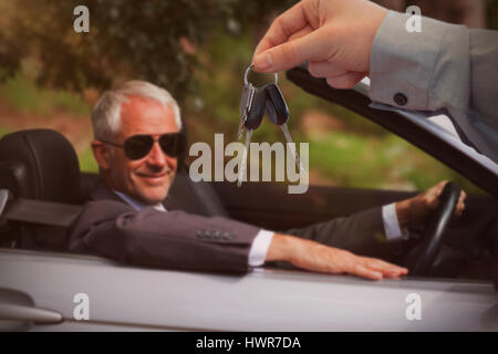 Les clés de la voiture de donner à un client contre smiling mature woman driving classy location Banque D'Images