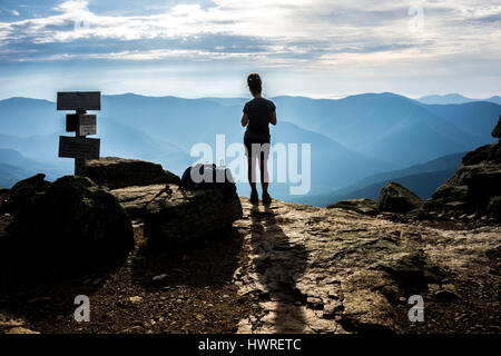 Un female hiker en silhouette marque une pause après une randonnée difficile en haut de Franconia Ridge sur le New Hampshire section du sentier des Appalaches. Banque D'Images