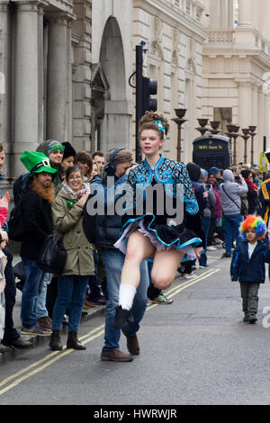 Danseur traditionnel irlandais en irlandais costume sauter et danser dans les rues de Londres pour le St Patricks day parade Banque D'Images