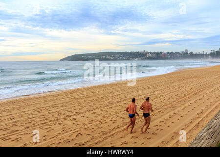 Personnes deux hommes s'exerçant en courant et en jogging sur Manly Beach à Dawn , Sydney, Australie Banque D'Images