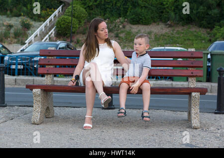 Jeune femme parle avec un enfant assis sur le banc Banque D'Images