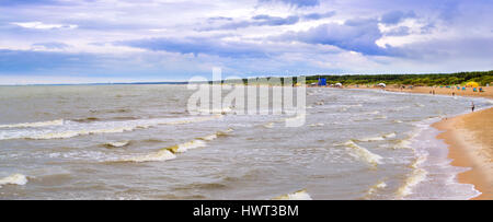 De fortes vagues sur un jour nuageux orageux baignée par la côte de la mer Baltique. Peu de touristes à pied le long d'une plage de sable de la station balnéaire de Palanga, Lituanie, Banque D'Images