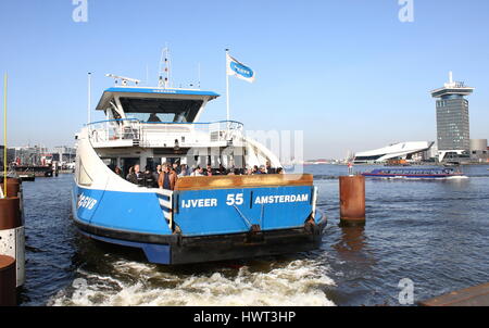 Traversée en ferry pour les piétons et les cyclistes à la rivière IJ derrière la gare centrale d'Amsterdam, Pays-Bas. Musée du film de l'œil et A'DAM tour en arrière-plan Banque D'Images