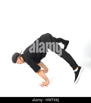 Jeune homme musclé se tient sur ses mains. Il porte des vêtements noirs et fond blanc snapback . Banque D'Images