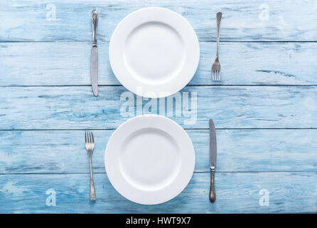 Deux assiettes et couverts vide blanc sur bleu table. Vue d'en haut. Banque D'Images