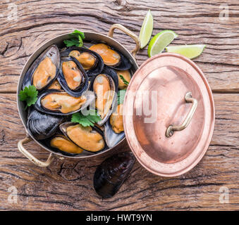 Les moules cuites en pan de cuivre sur la table en bois. Banque D'Images