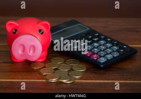 Pink piggy bank sitting on pile de pièces à côté de calculatrice Banque D'Images