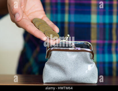 Les mains de womans face caméra, en plaçant des pièces de monnaie dans les petits porte-monnaie gris Banque D'Images