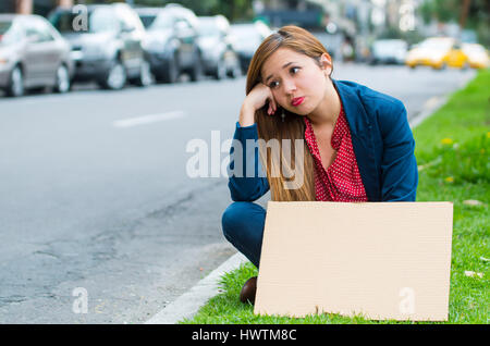 Jeune femme portant des vêtements décontractés sitting outdoors holding affiche en carton, protestant contre le concept Banque D'Images