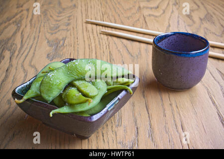 Bol en verre de saké d'edamame et baguettes Banque D'Images