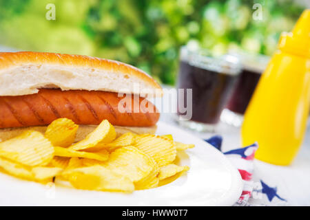 Un délicieux hot dog avec les chips de pomme de terre sur une table d'extérieur. Banque D'Images