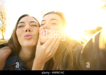 Funny friends un avec un périphérique inconnu selfies au lever du soleil avec la chaude lumière du soleil dans l'arrière-plan Banque D'Images