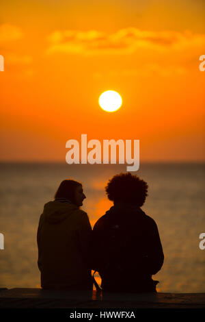 Pays de Galles Aberystwyth UK, jeudi 23 mars 2017 Royaume-Uni Météo : un couple s'asseoir et regarder le coucher de soleil spectaculaire sur la baie de Cardigan à Aberystwyth, sur la côte ouest du pays de Galles Crédit photo : Keith Morris/Alamy Live News Banque D'Images