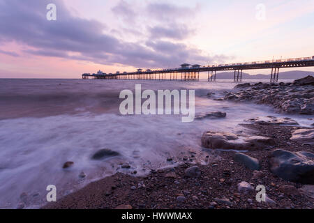 La pittoresque pier silhouetté contre le ciel à la populaire station balnéaire de Llandudno au lever du soleil, comme des vagues frapper doucement le rivage Banque D'Images