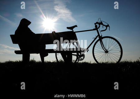 Düsseldorf, Allemagne. Mar 23, 2017. Un cycliste jouit d'un coucher de soleil sur un banc au Rhin bank à Duesseldorf, Allemagne, 23 mars 2017. Photo : Martin Gerten/dpa/Alamy Live News Banque D'Images