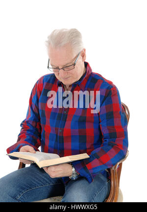 Cheveux blancs un vieillard assis dans un vieux fauteuil avec ses lunettes et studding sa bible, isolée pour fond blanc. Banque D'Images