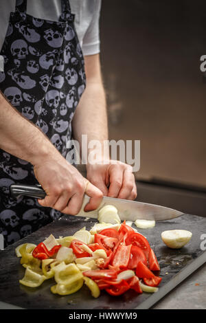 Chef est émincer les légumes sur une planche à découper noire dans la cuisine du restaurant Banque D'Images