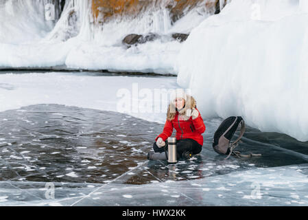 La fille est de boire le thé sur la glace. Banque D'Images