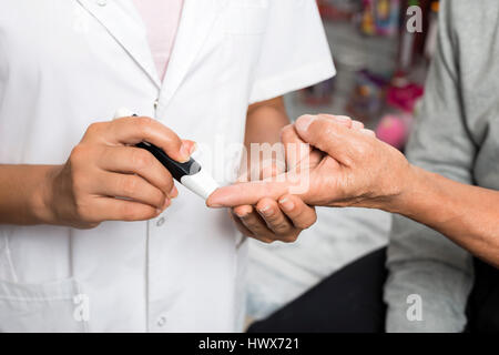 Portrait de femme médecin contrôle de niveau de sucre senior patient avec glucomètre en pharmacie Banque D'Images