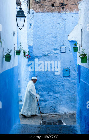 Chefchaouen, Maroc. Homme marchant avec une canne dans une rue étroite.