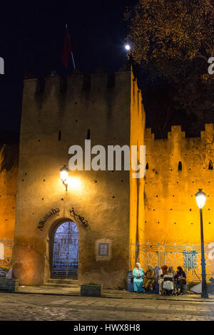 Chefchaouen, Maroc. Les femmes assises, parler à la place Outa El-Hammam, soir, par l'entrée de la Casbah, construite 1471. Banque D'Images