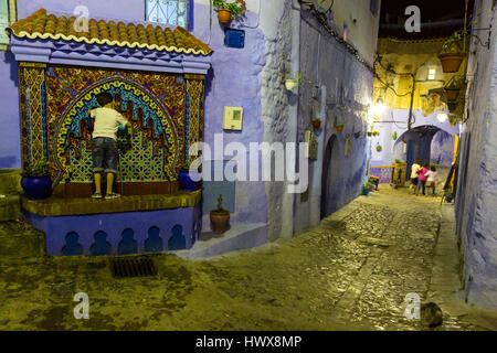 Chefchaouen, Maroc. Jeune garçon à fonction d'un robinet d'eau dans la Médina de nuit. Banque D'Images