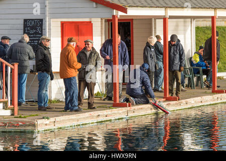 Un groupe d'hommes déjà rassembler pour naviguer leurs bateaux modèle radio-commandé sur un lac. Banque D'Images