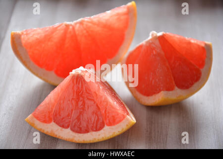 Tranches de pamplemousse rose sur une planche en bois Banque D'Images