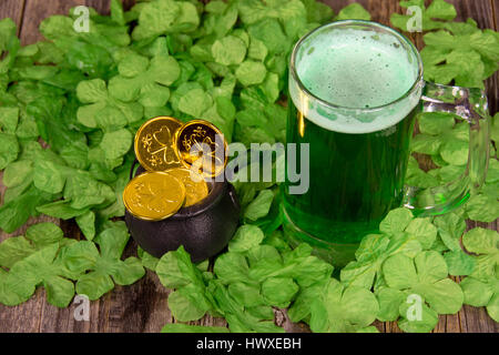 La bière verte avec des pièces d'or dans des trèfles irlandais Banque D'Images