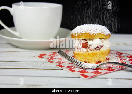 Fraise et crème fouettée remplissant couches de gâteau avec une fourchette et saupoudrer de sucre en poudre Banque D'Images