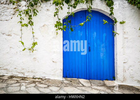 Grande porte bleue et un mur blanc où la puce pousse sur l'île de Crète, Grèce Banque D'Images