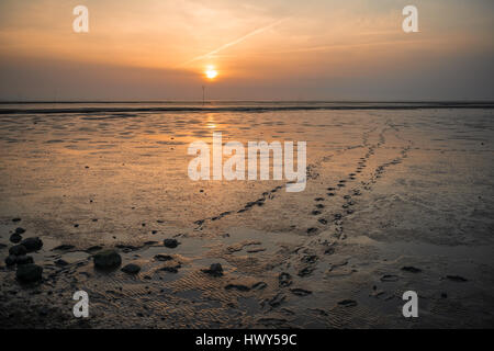 Empreintes de pas sur le sable près du phare sur Obereversand picturasque au coucher du soleil sur la mer du Nord Banque D'Images