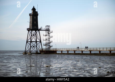 Bad Zwischenahn, Allemagne - 11 mars 2017 : les visiteurs de marcher le long de la Jetée du Phare au coucher du soleil en Obereversand pittoresque de la mer du Nord Banque D'Images