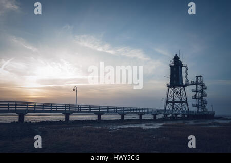 Bad Zwischenahn, Allemagne - 11 mars 2017 : les visiteurs de marcher le long de la Jetée du Phare au coucher du soleil en Obereversand pittoresque de la mer du Nord Banque D'Images