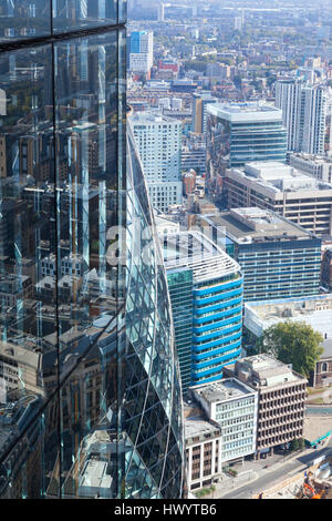 Vue aérienne de l'Est de Londres sur les toits de maisons et bureaux, avec des reflets de la ville dans un haut bâtiment de verre Banque D'Images