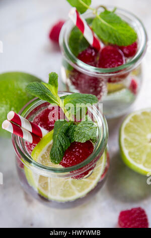 Verre de l'eau avec detox limes et rasperries décoré de feuilles de menthe Banque D'Images