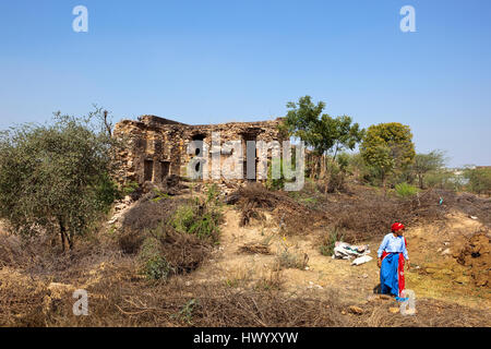 Des immeubles en ruines antiques sur une colline avec une femme en costume traditionnel près du Jal Mahal, Narnaul, au Rajasthan, Inde du Nord sous un ciel bleu Banque D'Images