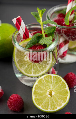 Verre de l'eau avec detox limes et rasperries décoré de feuilles de menthe Banque D'Images