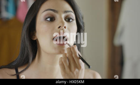 Low angle view of woman applying lipstick makeup in mirror Banque D'Images