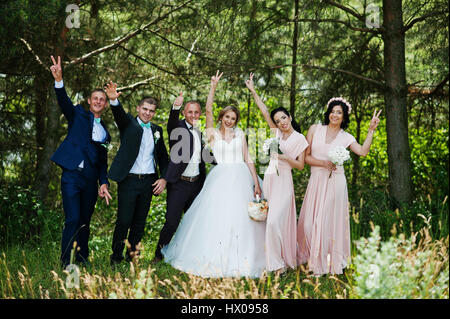 Couple de mariage à la mode à l'honneur sur rose robes et meilleur mans avec noeuds papillon turquoise à forest par beau jour de mariage mettent leurs mains sur le Banque D'Images