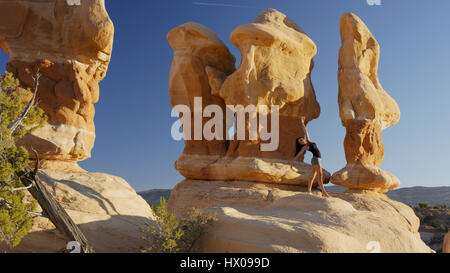 Low angle view of woman dancing et posant sur des rochers dans les désert paysage sous ciel bleu clair Banque D'Images