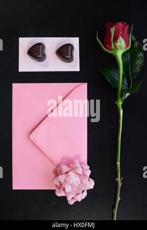 Tiré de l'enveloppe à côté de chocolat et rose rouge Banque D'Images