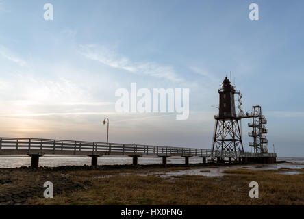 Bad Zwischenahn, Allemagne - 11 mars 2017 : les visiteurs de marcher le long de la Jetée du Phare au coucher du soleil en Obereversand pittoresque de la mer du Nord Banque D'Images