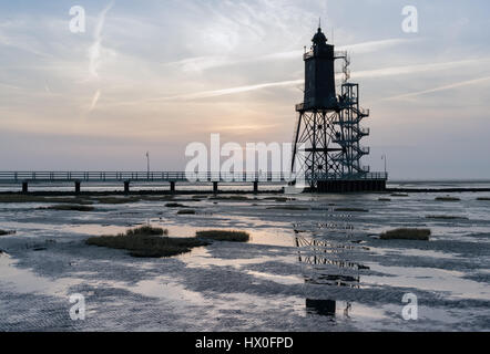 Bad Zwischenahn, Allemagne - 11 mars 2017 : les visiteurs de marcher le long de la Jetée du Phare au coucher du soleil en Obereversand pittoresque de la mer du Nord Banque D'Images