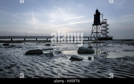 Bad Zwischenahn, Allemagne - 11 mars 2017 : les visiteurs de marcher le long de la Jetée du Phare au coucher du soleil en Obereversand pittoresque de la mer du Nord Banque D'Images