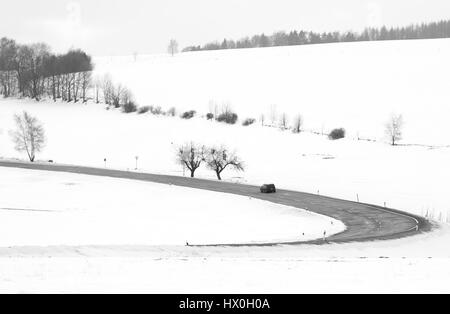 Noir et blanc minimaliste d'une vallée couverte de neige avec une route rurale Banque D'Images