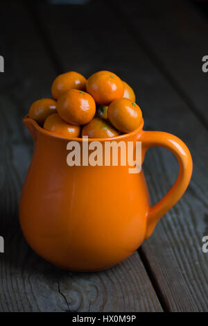 Pichet orange vif rempli de tangerines. Banque D'Images