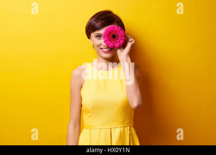 Jeune femme avec fleur en avant des yeux Banque D'Images